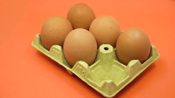 Hand Removing an Egg From an Open Egg Carton on Orange Background alt