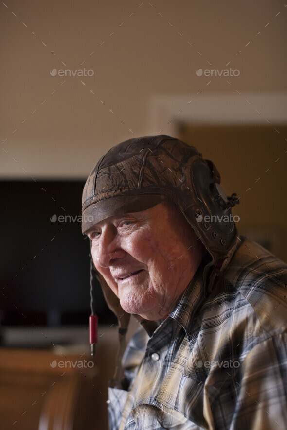 Senior man indoors wearing old leather football helmet Stock Photo by Image Source