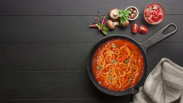Cooking homemade Italian pasta spaghetti with tomato sauce in cast iron pan