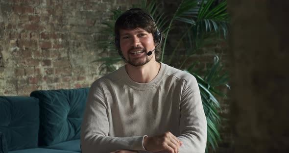 Happy Man in Headphones Looking at Camera Enjoying Video Meeting with Friends and Colleagues alt