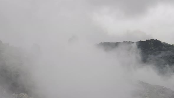 Photographer Amongst Thick Smoke On Rocks Of Lava Field alt