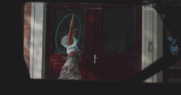 Woman Spins Hula Hoop infront of Red door alt