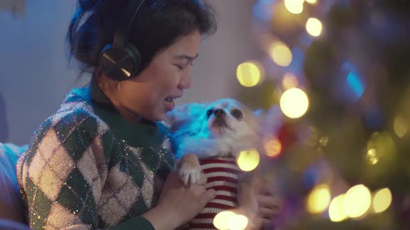 pretty asian female listen music frome headphone hand hug cute little lapdog