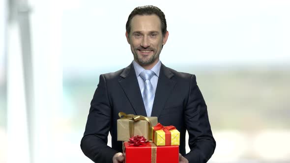 Smiling Businessman Holding Gift Boxes alt