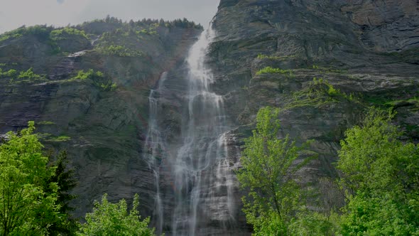 Stunning static shot of majestic waterfall fluent down the mountain in swiss region alt
