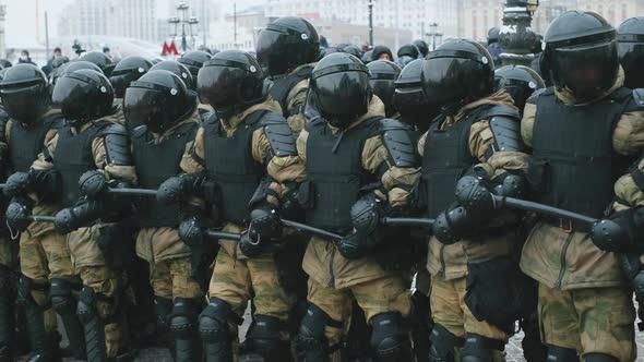 Armored Police Enforcers in Tinted Visors on Helmets with Batons Block Streets
