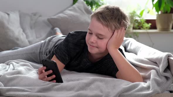 Boy Using Smart Phone Looking at Mobile Screen Making Conference Call in App alt