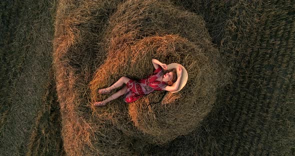 Girl Lying On A Pile Of Hay In A Field At Sunset alt
