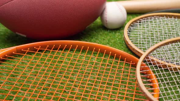 Sport Equipment Rackets Balls and Baseball Bat on Grass