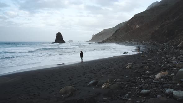 Young Man Tourist Goes Down the Long Stairs to the Famous Volcanic Black Sand Beach Benijo in the alt