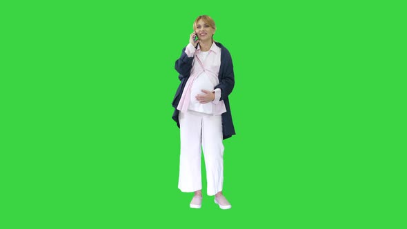 Attractive Pregnant Woman Making Phone Call and Holding Her Tummy on a Green Screen Chroma Key alt