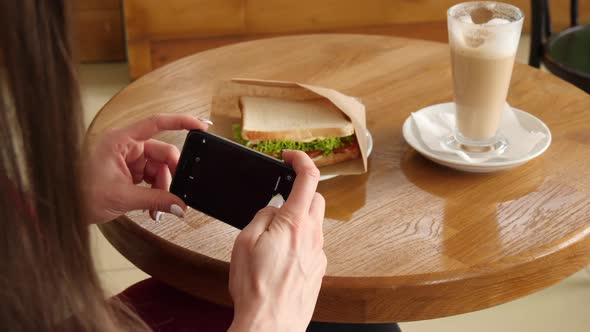 Trendy Woman Wearing Red Dress in a Cafe Make Photo of Sandwich Food with Mobile Phone Camera alt