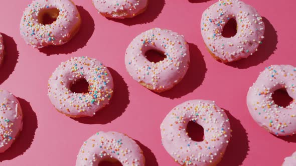 Video of donuts with icing on pink background alt