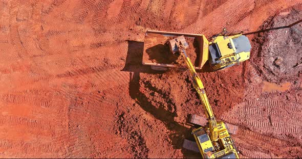 Aerial Top Down View of an Excavator Loading Earth Into a Dump Truck alt