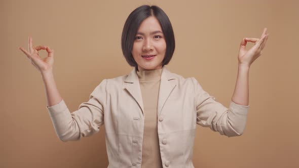 Asian business woman calms down, breathes deeply with meditating holding her hands in yoga gesture