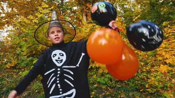 A Boy with Orange Black Inflatable Balloons in a Wizard Costume Waves His Hands During Halloween