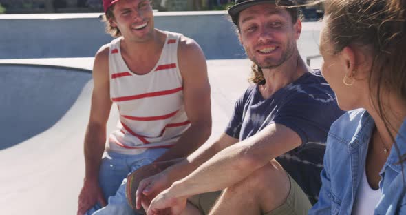 Happy caucasian woman and two male friends sitting, talking and spending time together on sunny day alt