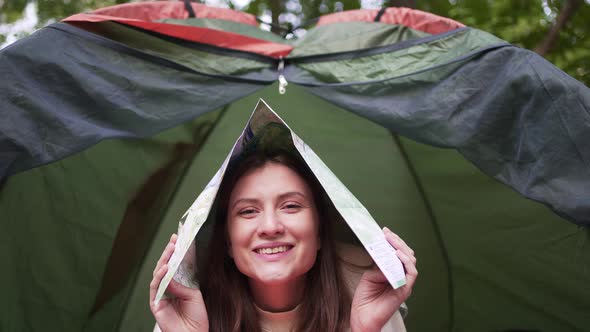 Beautiful Young Woman Fooling Around with a Map in a Tent