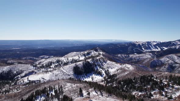 High altitude drone aerial view of mountains and snowy valleys in NM, US alt