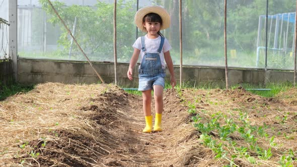 Little girl wearing a hat helps her mother in the garden, a little gardener. alt