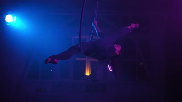 Silhouette Aerial Gymnast Performs Trick in Ring in Smoky Room with Backlit alt