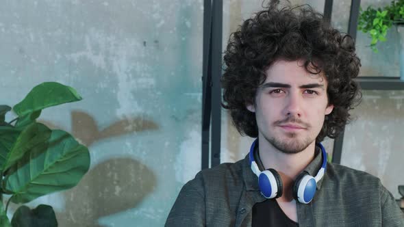 Handsome Young Curly Haired Guy Looking at the Camera with a Happy Facial Expression alt