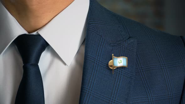 Businessman Walking Towards Camera With Country Flag Pin Guatemala alt