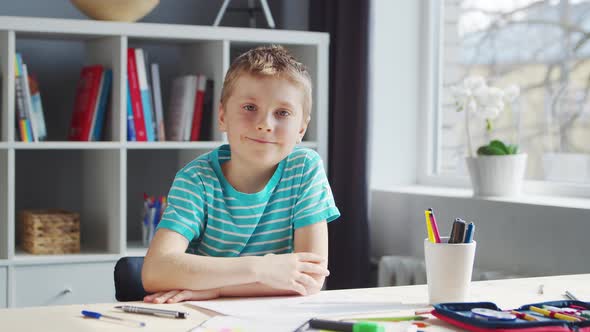 Boy is Doing  Homework at the Table. Cute Child is Learning at Home. alt