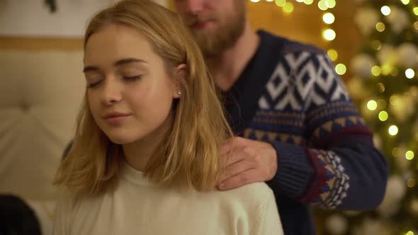 New Year Shoot of Happy Young Couple Handsome Man Doing Shoulders Massage to His Attractive alt