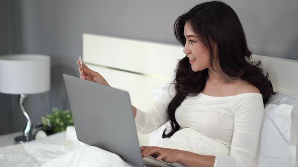 woman shopping online with credit card and laptop computer on a bed