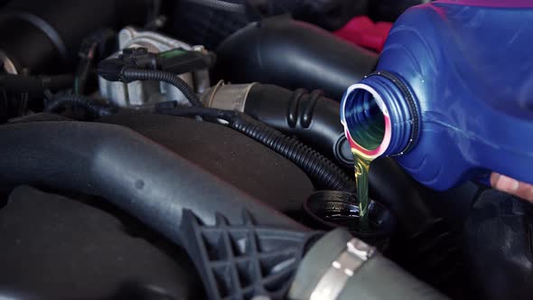 New Engine Oil Is Pouring Into The Car Engine At Workshop 1 alt