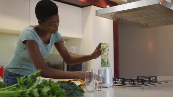 African american attractive woman blending ingredients for smoothie in kitchen alt