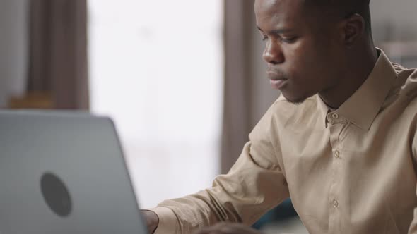 Black Male Student is Working with Laptop Sending Message in Social Nets or in Work Chat Portrait alt
