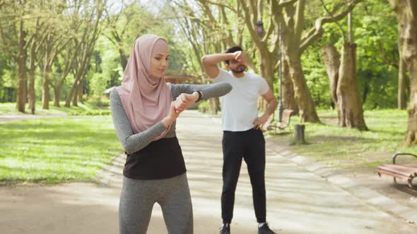 Woman in Hijab Checking Time on Smart Watch While Muslim Guy Relaxing After alt