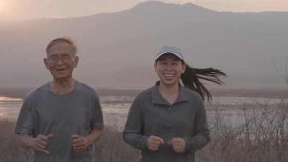 Grandfather and granddaughter are jogging by the lake at sunset and tell stories of past life experi alt
