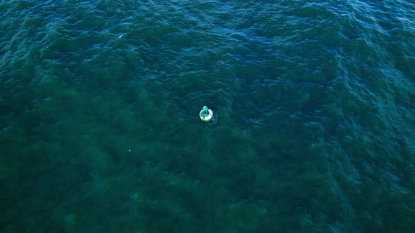 Aerial 4k drone footage circling a buoy bobbling in the waves near the coastline