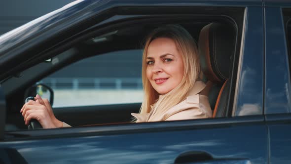 The Woman Is Sitting Behinde the Wheel of the Brandnew Car. She Is Looking Happy. alt