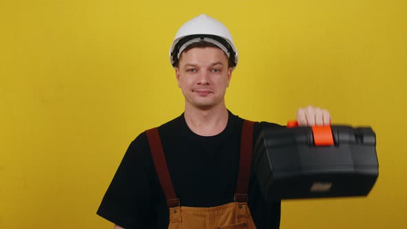 Happy Worker in Uniform and Hard Hat Holding Tool Box and Showing Thumbs Up alt