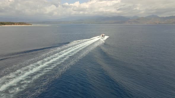 Aerial tracking shot of speedboat passing the Indian Ocean during sunny and cloudy weather. alt