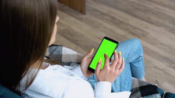 Happy Young Woman Using Mobile Phone While Sitting a Couch at Home alt
