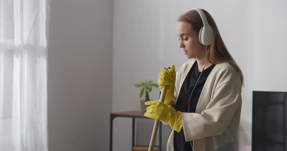 Housewife Is Singing Song and Dancing with Mop in Living Room Cleanup and Housekeeping Medium alt