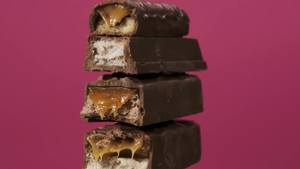 Four Candy Bars Spin on Pink Background. The Unpacked Sweets Close Up Macro Shot. Nougat and Caramel alt
