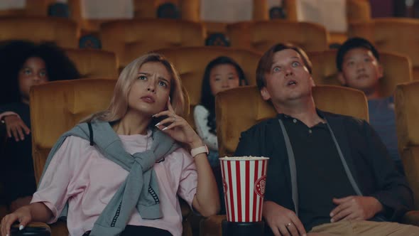 Attractive cheerful young caucasian woman watching horror movie in cinema theater.