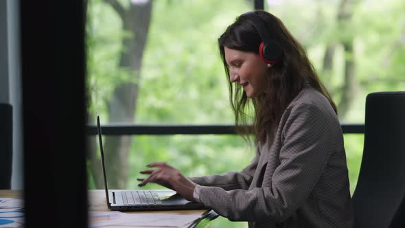 Confident Positive Woman Listening to Music in Headphones Smiling Typing on Laptop Keyboard in alt