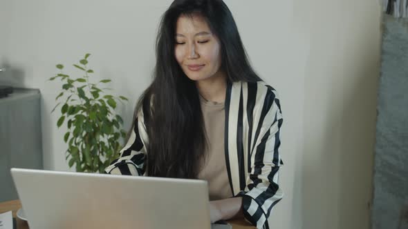Successful Freelancer Asian Lady Using Laptop Computer Working at Home in Kitchen alt