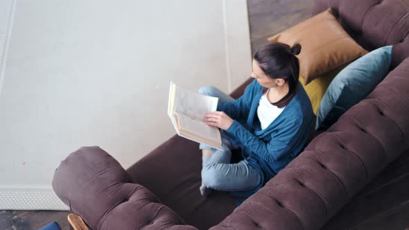 High Angle Smiling Casual Young Woman Enthusiastically Reading Book Turning Page alt