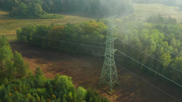 Turn Around High Voltage Electric Transmission Tower or Pylon on the Terrain Through the Clouds alt