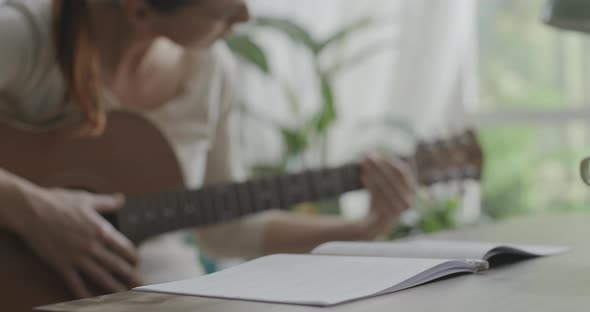 Woman playing guitar at home and composing music