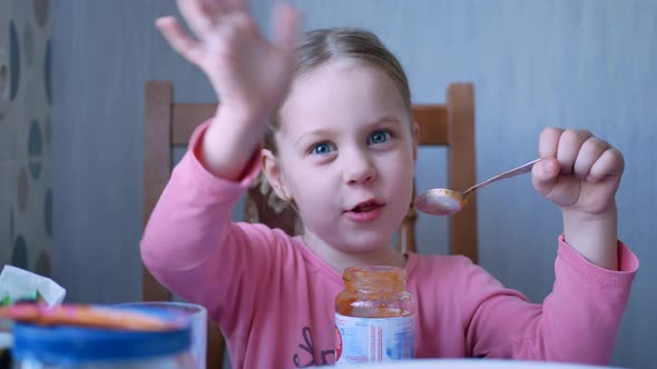 Beautiful Little Girl Kid Eats By Spoon Fruit Puree or Sauce