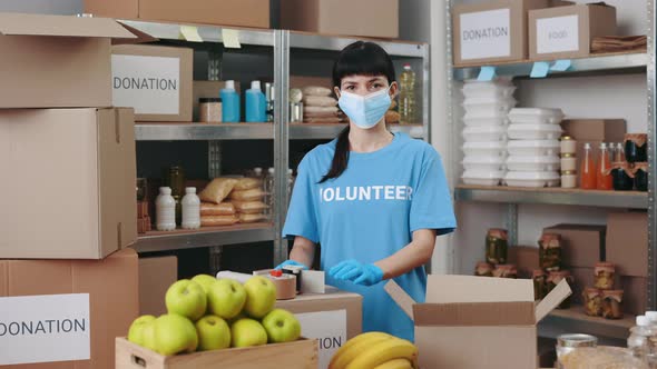 Female Volunteer in Face Mask and Gloves Posing at Food Bank alt
